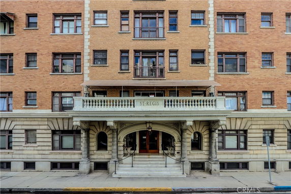 Front elevation of a multi-story brick building with a covered entrance and ornate columns.