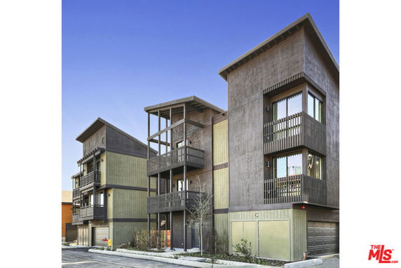 Front view of a multi-story modern residential building with balconies and distinct architectural lines.