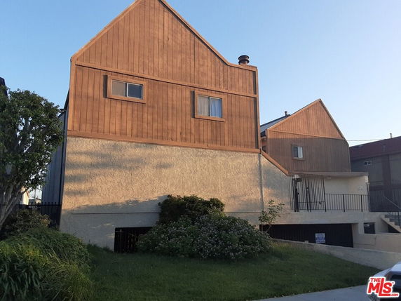Front view of a two-story house with a wooden upper facade and ground floor entrance.