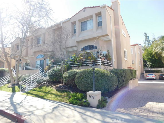 Front view of a multi-story house with a tiered garden and staircase.