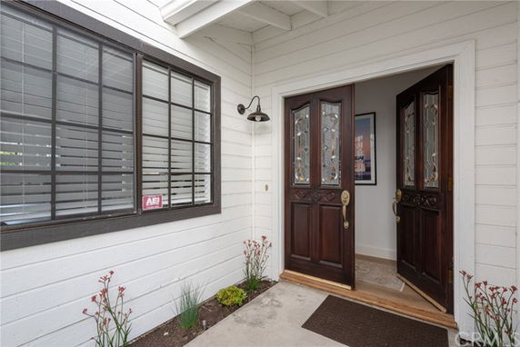 Front view of a house entrance with a double wooden door and adjacent window.