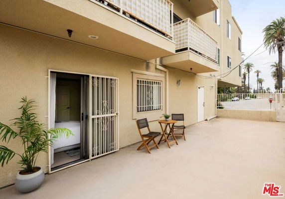 Front view of a multi-story building with balcony and outdoor seating area.