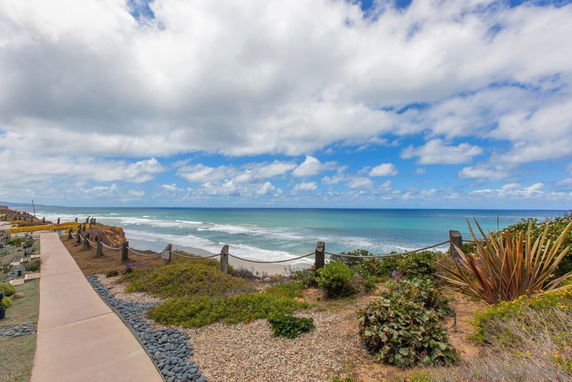 Panoramic view of a coastline with a pathway and ocean waves.