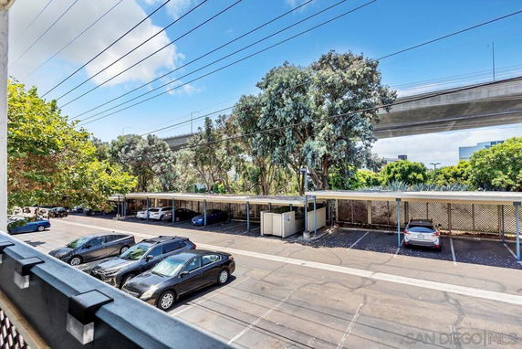 Outdoor parking area with covered parking spaces and several cars.