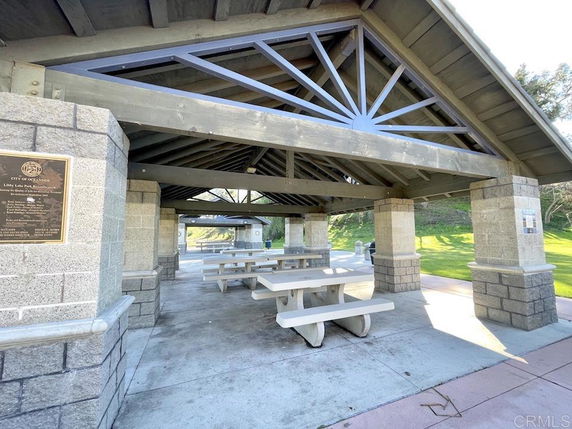 Covered outdoor structure with picnic tables and stone pillars.