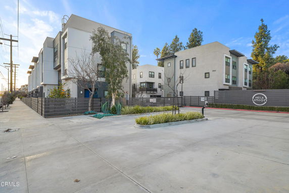 Front view of a modern multi-story residential complex with a gated entrance.