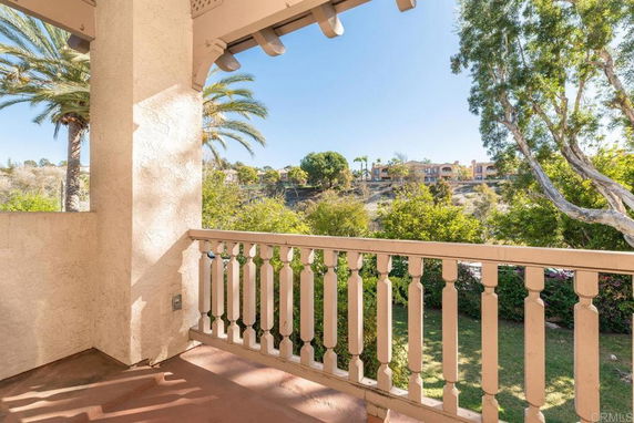 View from a balcony overlooking trees and distant buildings.