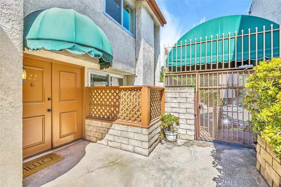 Front view of a house entrance with a green awning and lattice fence.