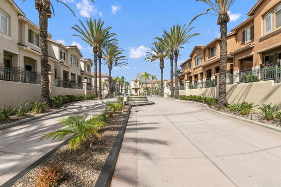 View of a residential area with townhouses and palm trees along a wide walkway.