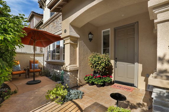 Front view of a house entrance with a covered porch and an outdoor seating area.