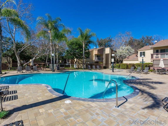 Outdoor swimming pool surrounded by trees and residential buildings.