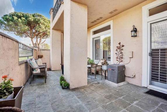 Outdoor patio area with seating and a view of trees beyond a low wall.