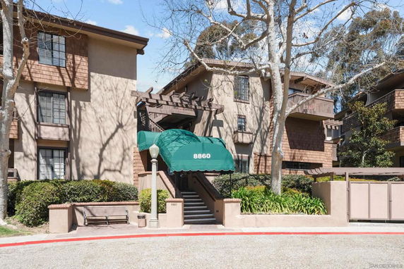 Front view of a multi-story building entrance with green awning and brick exterior.