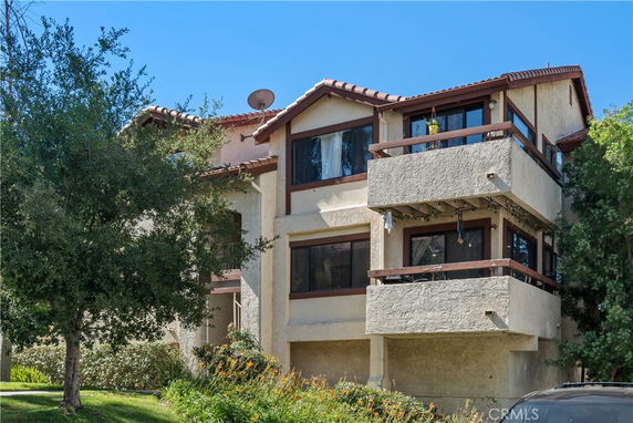 Front view of a multi-story building with balconies and a red-tiled roof.