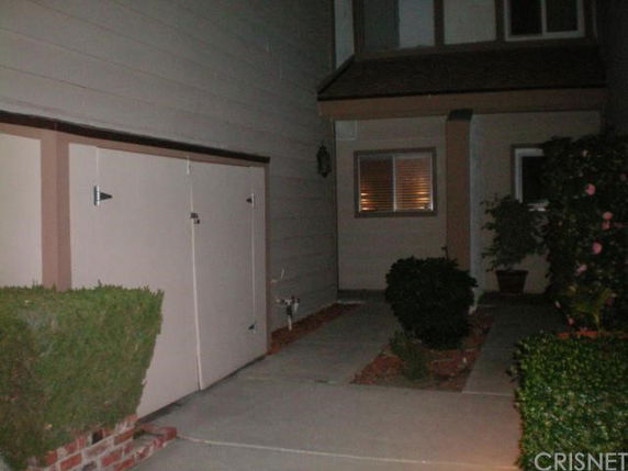 Front view of a house with an entrance and adjacent storage area.