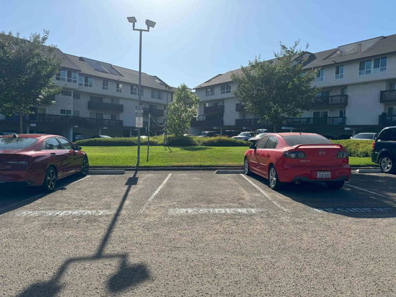 Outdoor parking area in front of multi-story residential buildings.