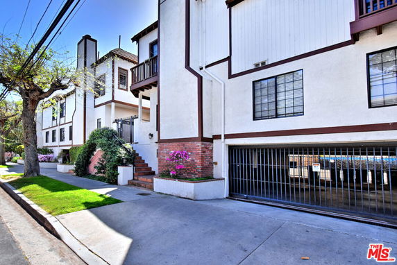 Front view of a multi-story building with a partially enclosed parking entrance.