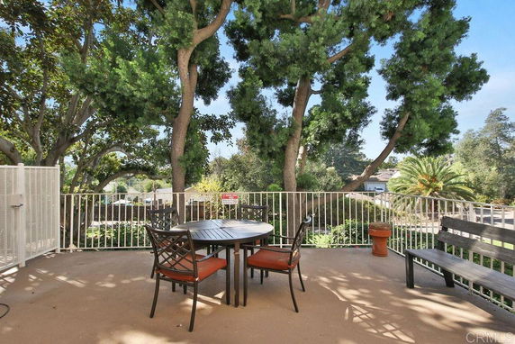 Outdoor seating area with a round table and chairs, surrounded by trees and greenery.