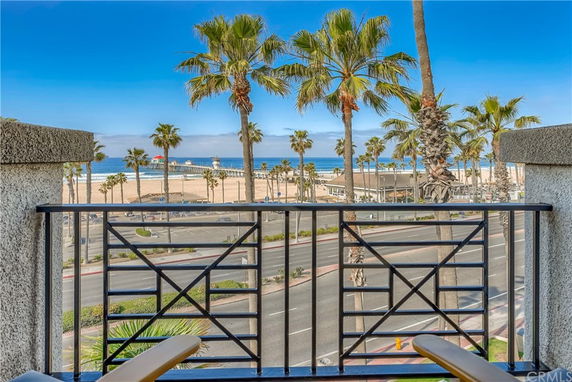 Panoramic view from a balcony overlooking a beach and ocean with palm trees.