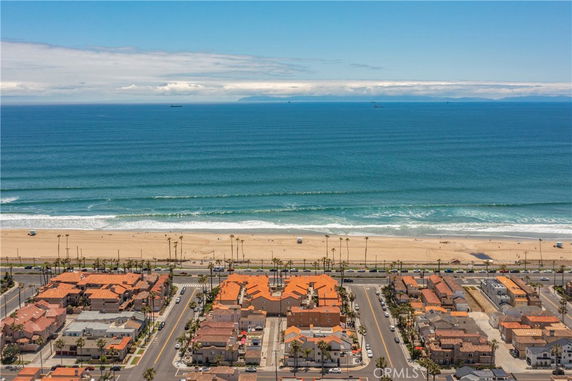 Panoramic view of a beachfront area with orange-roofed buildings and a sandy beach.
