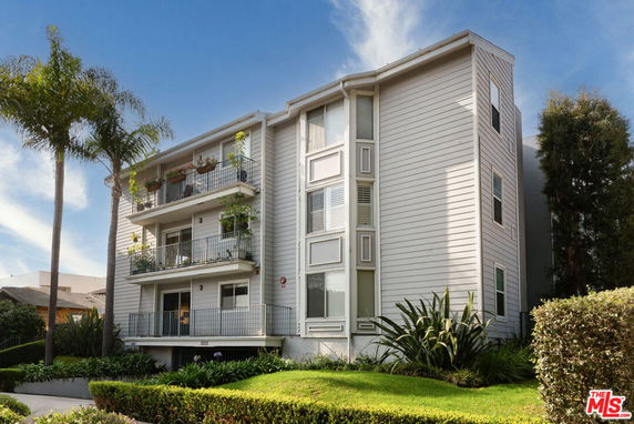 Front view of a multi-story residential building with balconies and white siding.