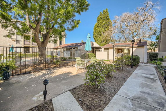 Outdoor area with a swimming pool and patio furniture surrounded by trees and buildings.