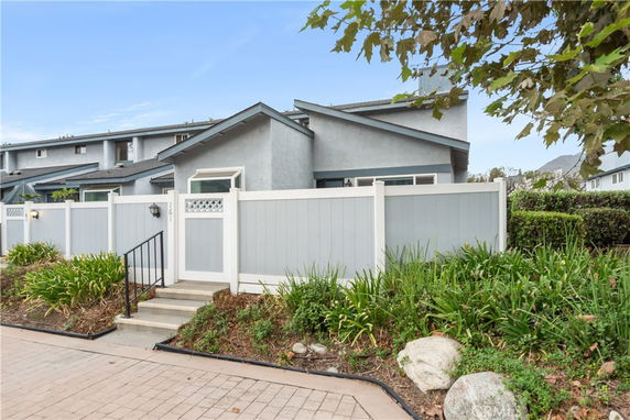 Front view of a two-story house with a gated entrance and surrounding fence.