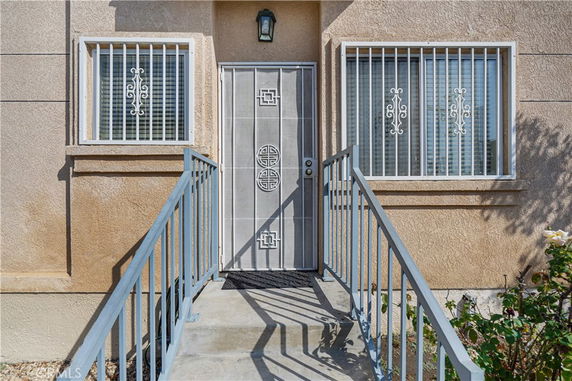 Entrance of a house with a metal security door and barred windows.