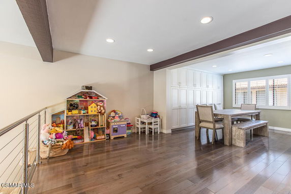Room with toys and a dining table, featuring storage cabinets and a window.