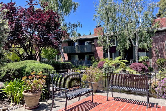 Front view of a multi-story brick building with balconies and a garden area.