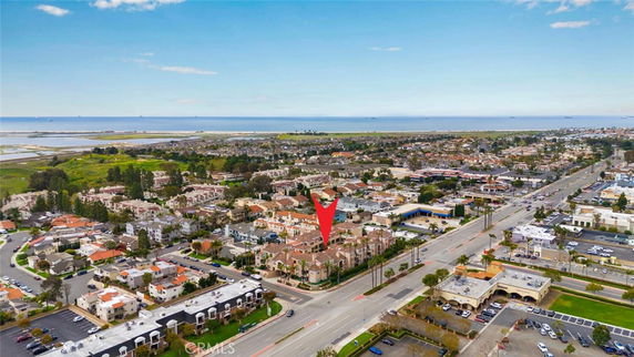 Aerial view of a residential neighborhood with various houses and a distant view of the ocean.
