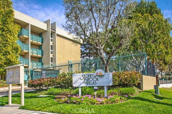 Front view of a multi-story residential building with balconies and a sign for Stoney Brook Villas.