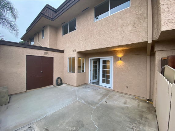 Front view of a two-story building with a patio and double patio doors.