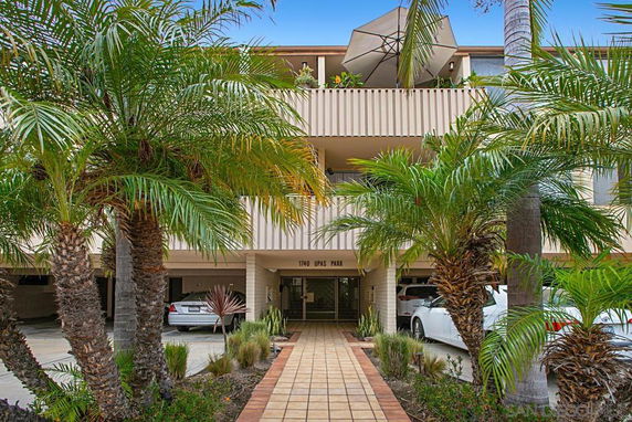 Front view of a multi-story building with balconies and a garden path leading to the entrance.