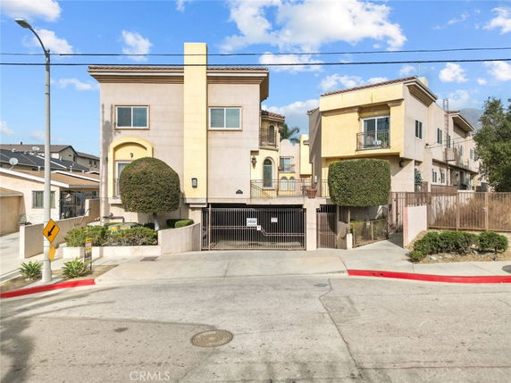 Front view of a multi-story residential building with gated parking area.