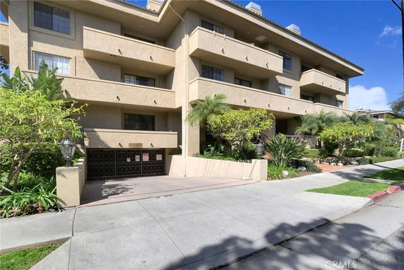 Front view of a multi-story residential building with balconies and a garage entrance.