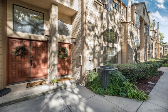 Front view of a multi-story residential building with decorative wreaths on doors.