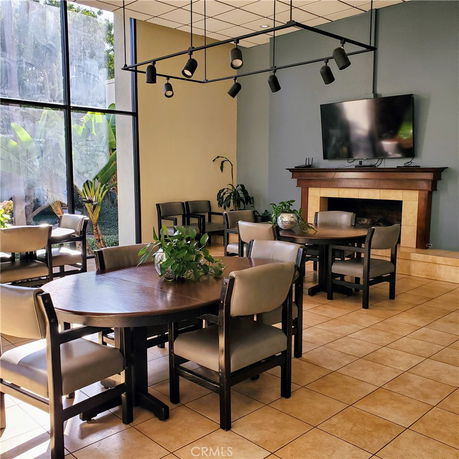 Indoor clubhouse area with tables, chairs, a fireplace, and a television.