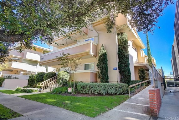 Front view of a multi-story building with balconies and stairs leading to the entrance.
