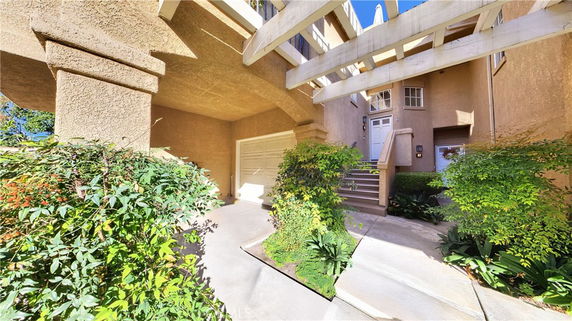 Front view of a house with garage entrance and stairs leading to the main door.