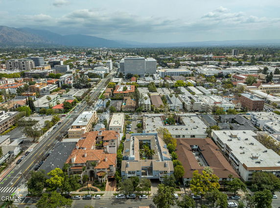 Aerial view of a cityscape with buildings and roads under a cloudy sky.