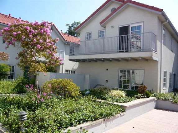 Front view of a two-story house with a balcony and red-tiled roof.