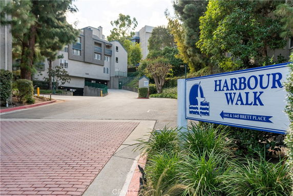 Front view of a multi-story residential building with a driveway and greenery.