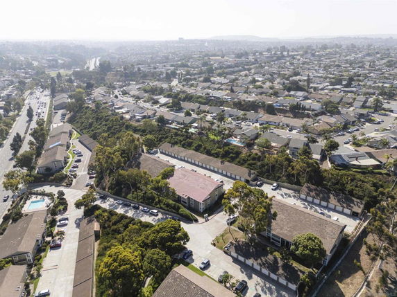 Aerial view of a residential area with multiple buildings, roads, and surrounding greenery.