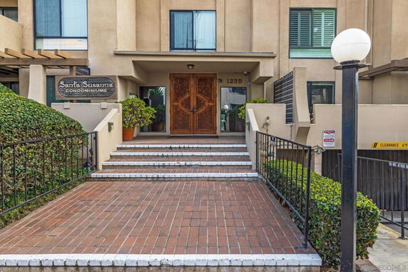 Front view of a condominium building with steps leading to ornate wooden doors.