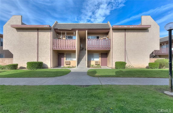 Front view of a two-story residential building with balconies and a central staircase.