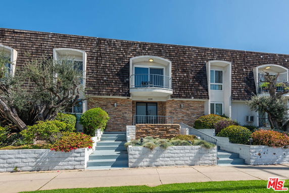 Front view of a two-story building with balconies and a stone facade.