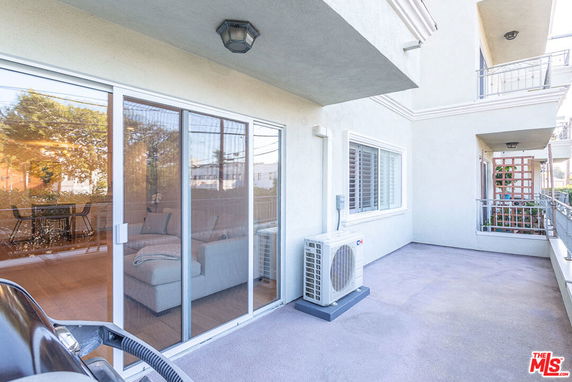 Outdoor patio area with sliding glass doors and an air conditioning unit attached to the wall.