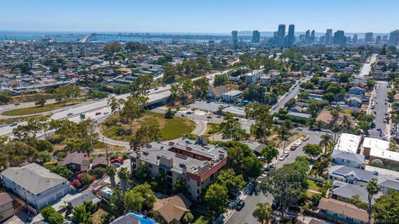 Aerial view of a cityscape with roads, houses, and a bridge in the distance.