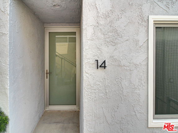 Front view of a house entrance with a door and a window on a textured wall.